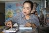 A woman is calculating bills for clients in her shop in Cambodia.  